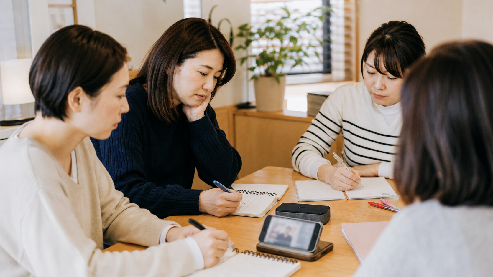 韓国語レッスンで音を聞きながらメモを取る30代女性たち